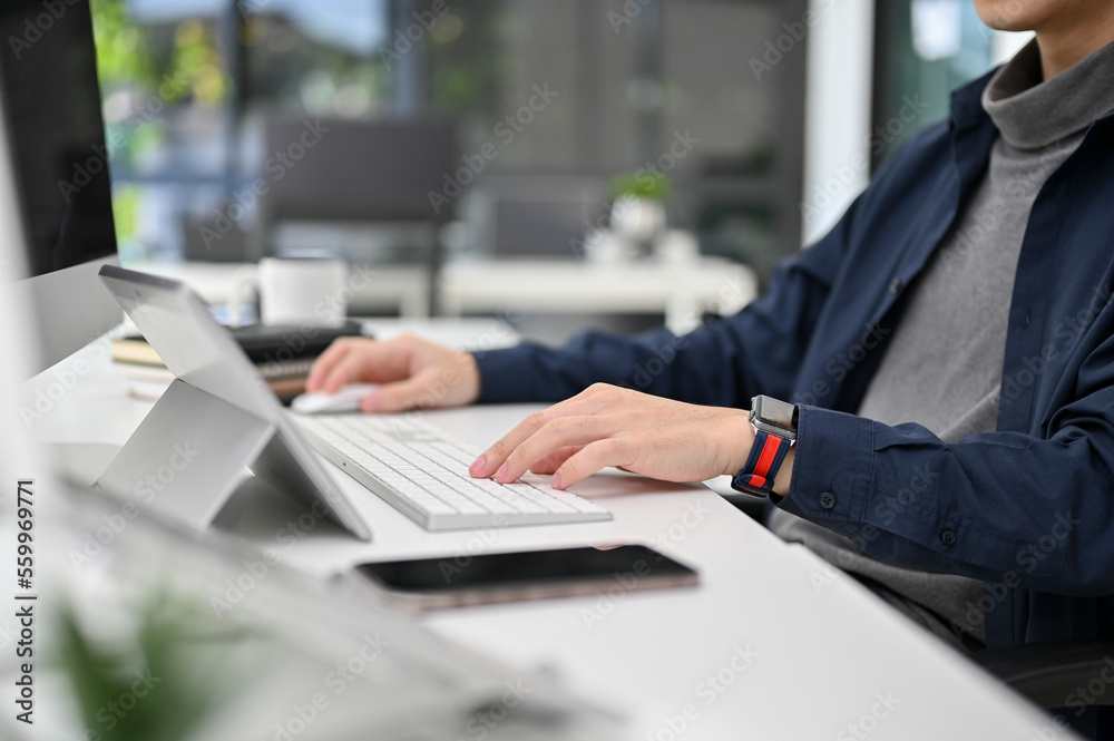 cropped, Asian male developer or programmer working at her desk, typing on keyboard. cropped, Asian male developer or programmer working at her desk, typing on keyboard.