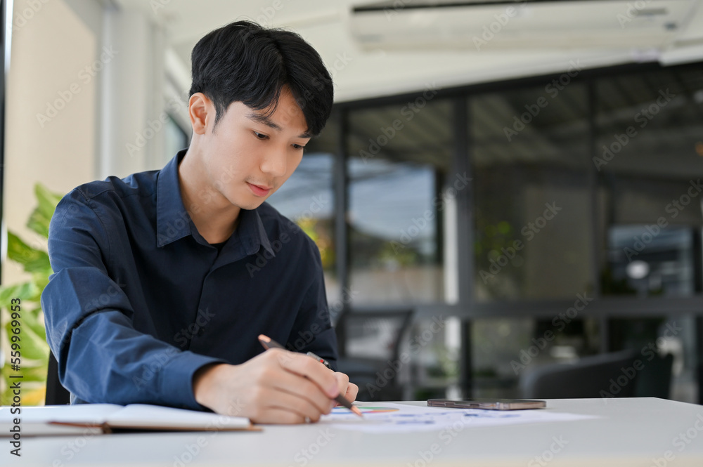 Concentrated Asian male financial analyst working on financial report, analyzing financial data Concentrated Asian male financial analyst working on financial report, analyzing financial data