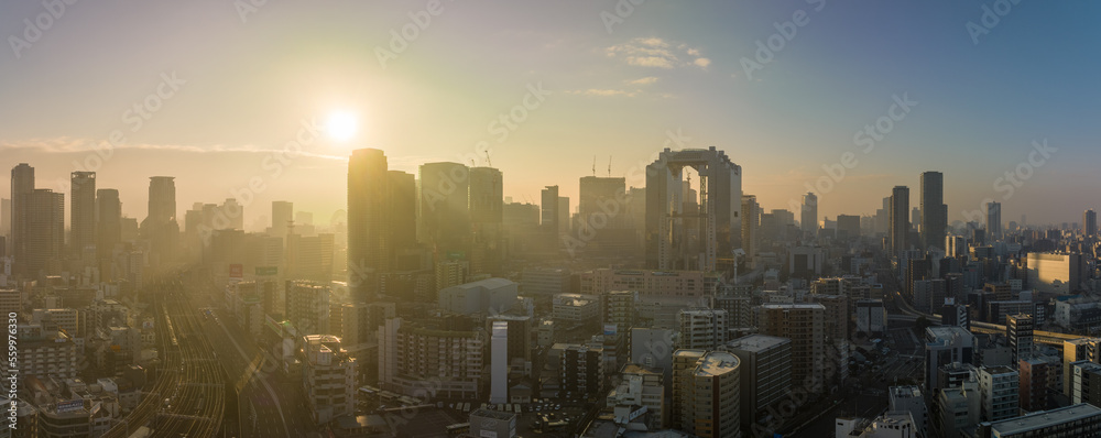 Bright sun rays through haze over downtown Osaka skyline in early morning