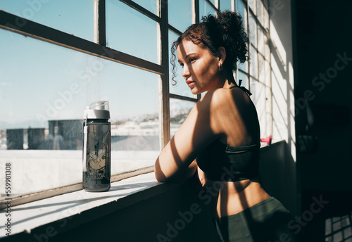 Obraz na plátne View, exercise and relax with a sports woman looking out of a window during a break in the gym for fitness