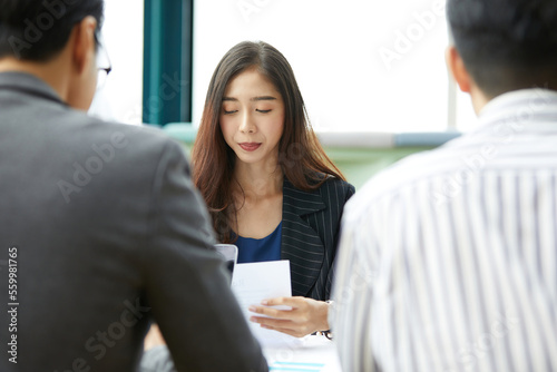 businesswoman reading or looking paper document with colleague in the office