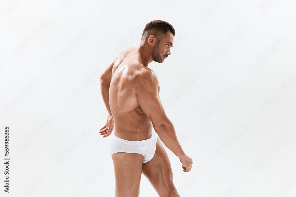 Man athletic body bodybuilder in briefs with naked torso abs full-length in the background, fitness classes. Advertising, sports, active lifestyle, competition, challenge concept. Man athletic body bodybuilder in briefs with naked torso abs full-length in the background, fitness classes. Advertising, sports, active lifestyle, competition, challenge concept.