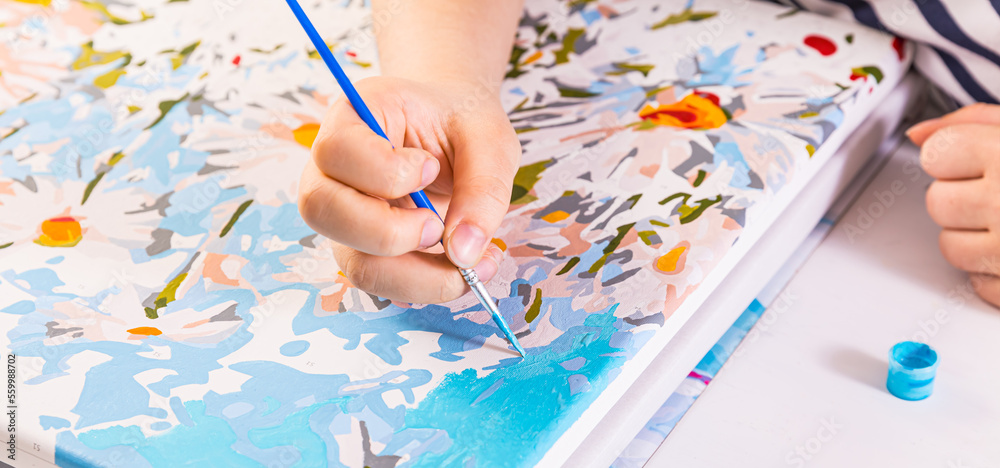 A hand with brush drawing picture of flowers with acrylic paints on canvas. Art concept. A hand with brush drawing picture of flowers with acrylic paints on canvas. Art concept.
