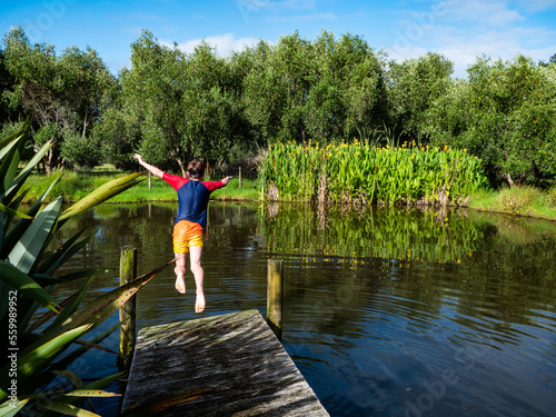 A boy is jumping into a natural pond during summer
