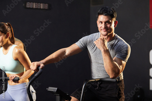 young athletic man cycling exercise bikes at the gym