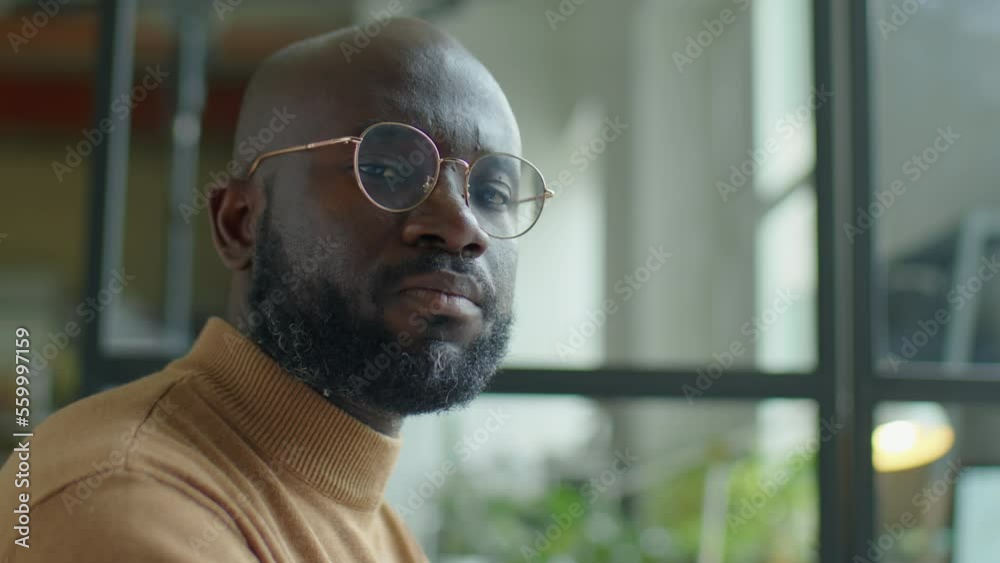 Portrait of African American businessman in eyeglasses posing for camera during workday in office Portrait of African American businessman in eyeglasses posing for camera during workday in office