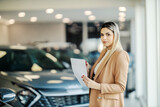 Car dealer is standing at the showroom and finishing contract.