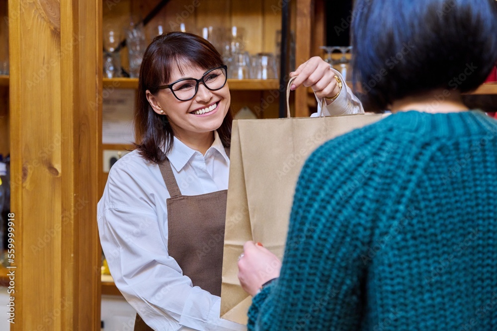 Φωτογραφία Woman restaurant worker issuing an order for takeaway food in paper bag