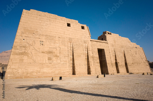 Ancient Egyptian temple Medinet Habu, dedicated to Amun, First Pylon of Mortuary Temple of Ramesses III and palm tree shadow