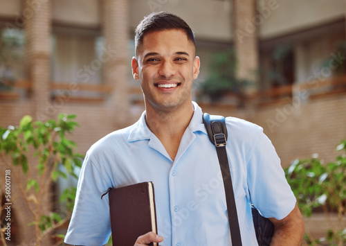 Face portrait, man and university student in campus ready for learning. Education, college and happy male learner from Brazil holding book for knowledge, studying and literature research outdoors.