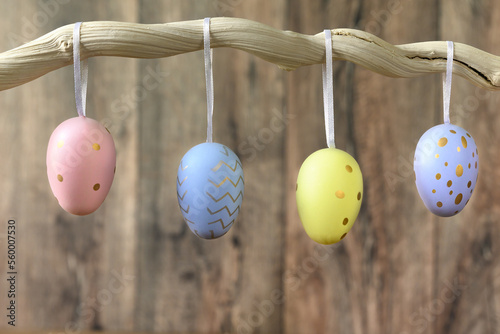Painted Easter eggs hang on branch against dark wooden background