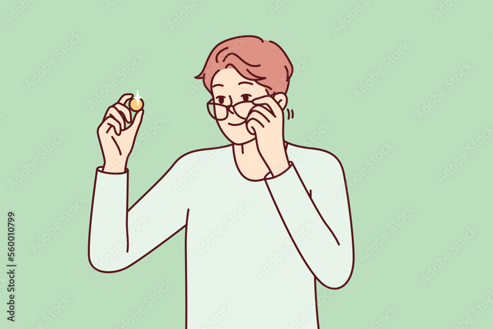 Fototapeta premium Positive man examines gold coin or piece of jewelry and lowers glasses from eyes to view rare exhibit. Guy is fond of numismatics and collecting coins from precious metals. Flat vector design 