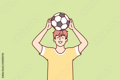 Teenage boy raises soccer ball over head dreams of becoming professional football player and playing in Major League. Young guy in yellow T-shirt stands on green lawn. Flat vector illustration