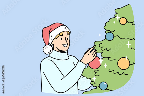 Smiling young man in Santa hat decorate Christmas tree with colorful balls. Happy guy have fun with fir-tree decoration at home celebrate New Year. Vector illustration. 