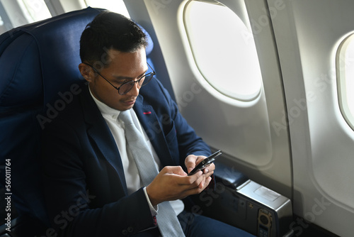 Confident businessman passenger checking news on smart phone, using wireless connection on board during flight © Prathankarnpap