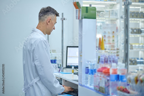Male pharmacist in lab coat working in a drugstore