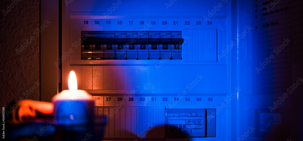 hand holding a candle near an electrical switchboard. Blackout concept hand holding a candle near an electrical switchboard. Blackout concept