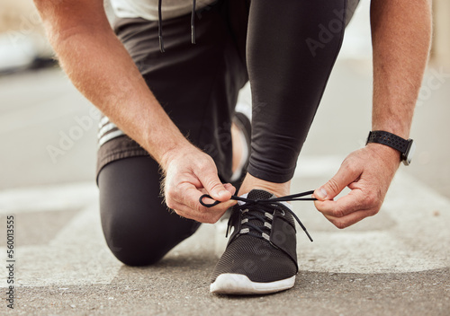 Training, fitness or hands tie shoes to start cardio workout or sports exercise on ground or city road. Legs, runner or healthy sports man with running shoes or footwear laces ready for body goals