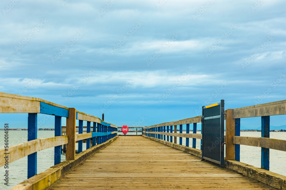 Wooden pier with sea and blue sky at the background. A wooden pier or jetty heading toward the horizon