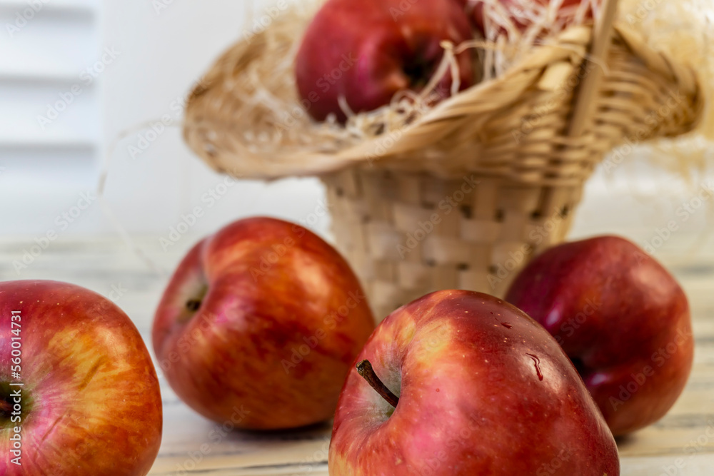 Red apples in a basket and on a wooden table Red apples in a basket and on a wooden table