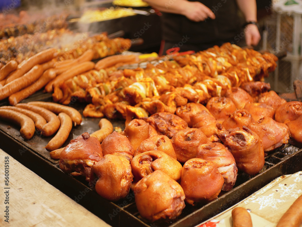 Slightly blurred pork knuckles, skewers and sausages on a huge grill, on the Krakow christmas market.