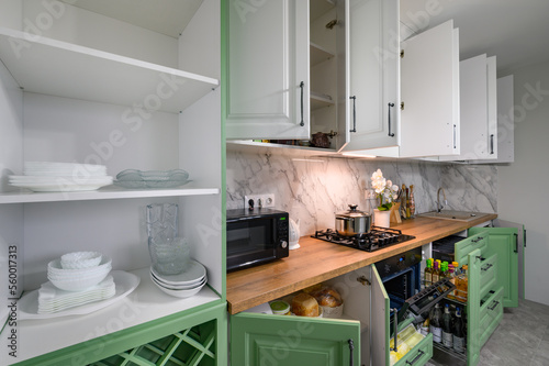 Doors open and drawers pulled out at new green and white kitchen furniture
