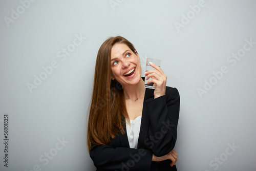 Smiling woman holding water glass looking up. isolated female portrait with black suit.