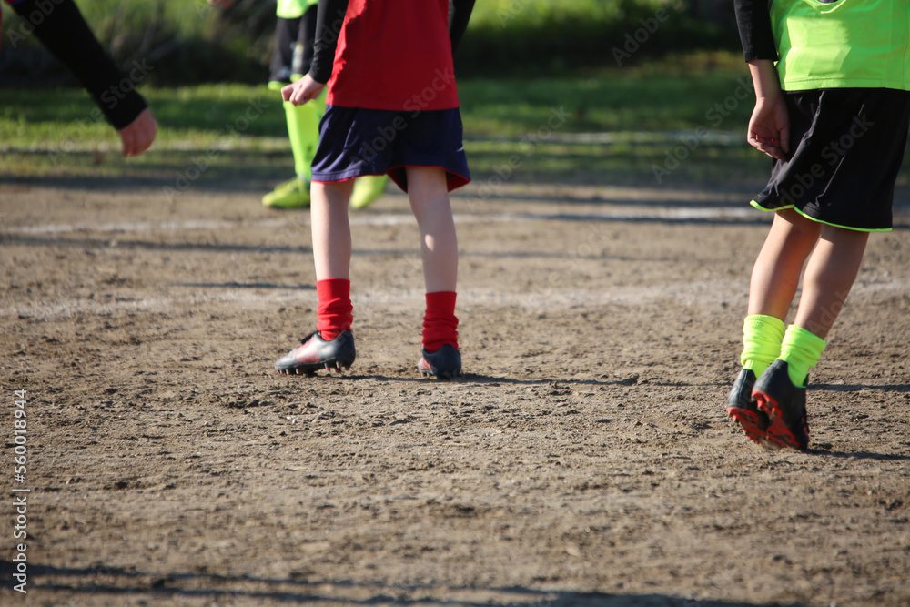 kicking a ball on a clay field with boys playing in the background kicking a ball on a clay field with boys playing in the background
