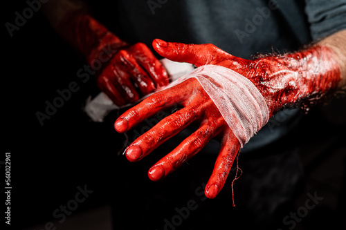 Obraz na plátne A man covered in blood bandages his hands.