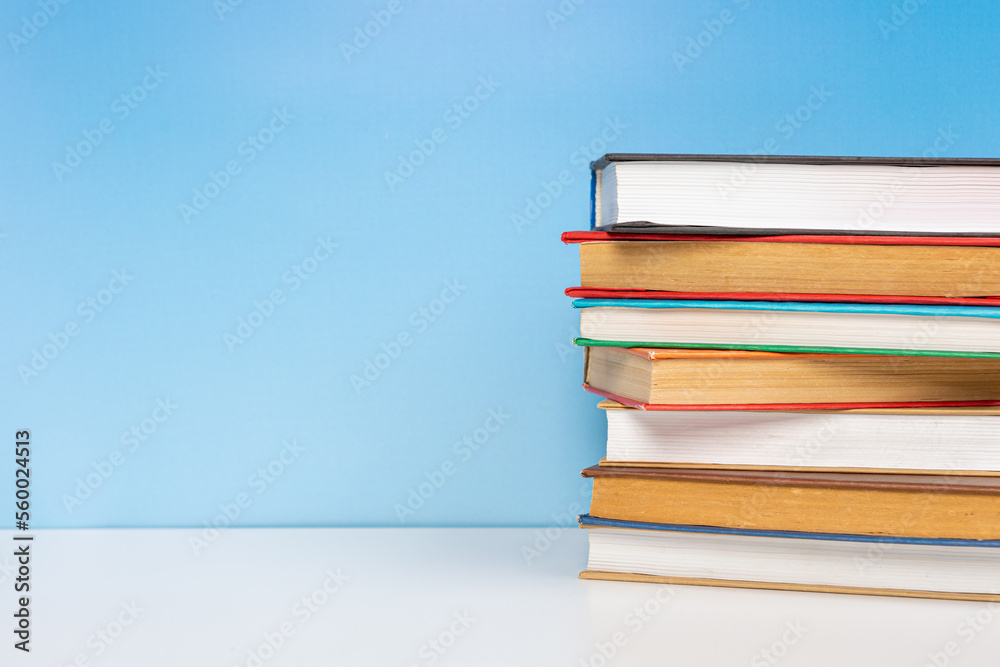 Stack of books in the colored cover lay on the wooden table and blue backround. Education learning concept Stack of books in the colored cover lay on the wooden table and blue backround. Education learning concept
