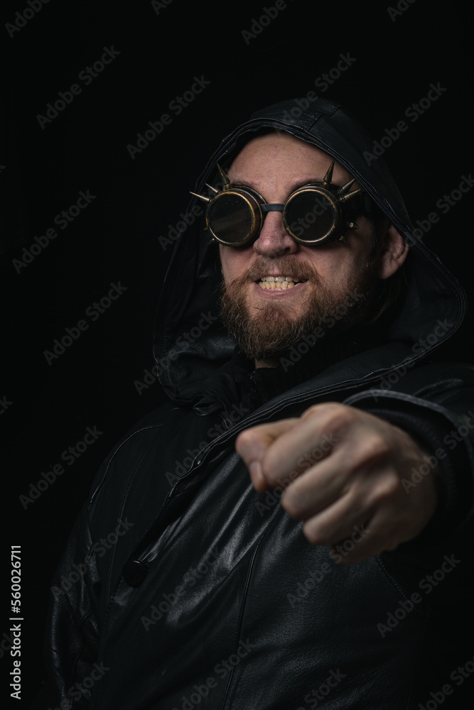 Fototapeta premium A man in a hood, wearing vintage steampunk goggles looking at the camera close-up