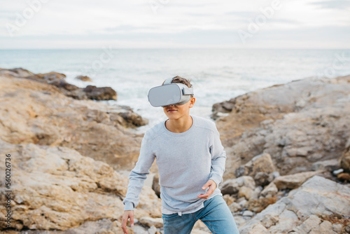 Boy Wearing Virtual Reality headset simulator on a rock breakwater, by the sea