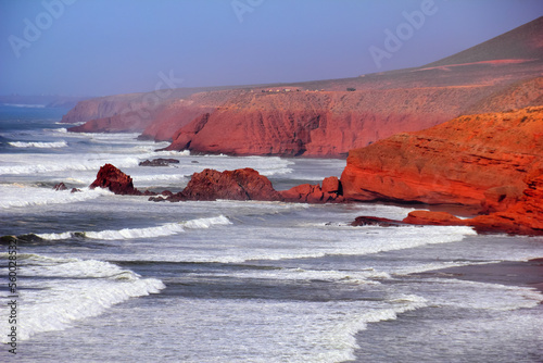 Rocky coast of Atlantic ocean, waves, sea surf, red rocks, ruins of famous mountain arch and blue evening sky. Beautiful nature view in Legzira beach, Sidi Ifni, Morocco, North West Africa.