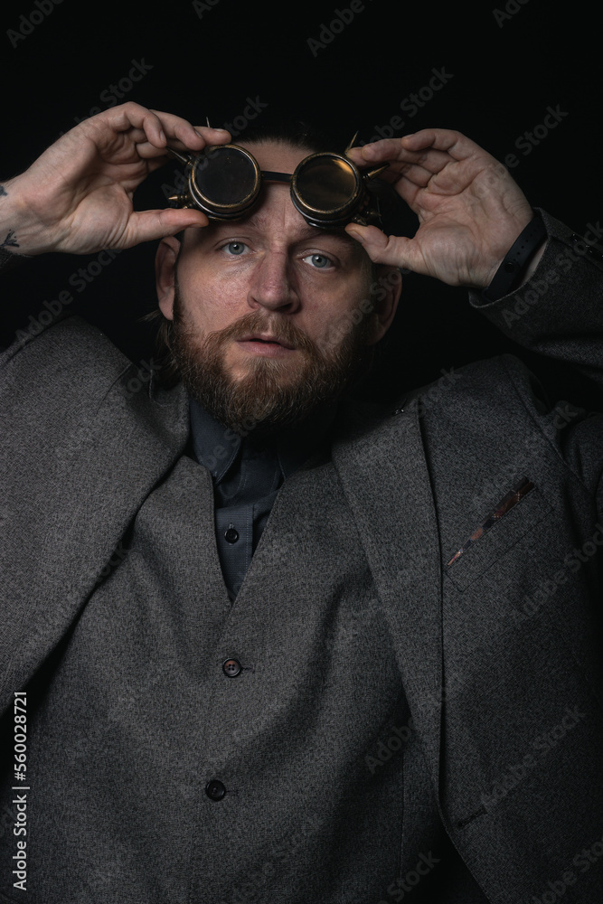 Obraz premium charismatic man in a classic suit and steampunk goggles on a black background stylish Portrait