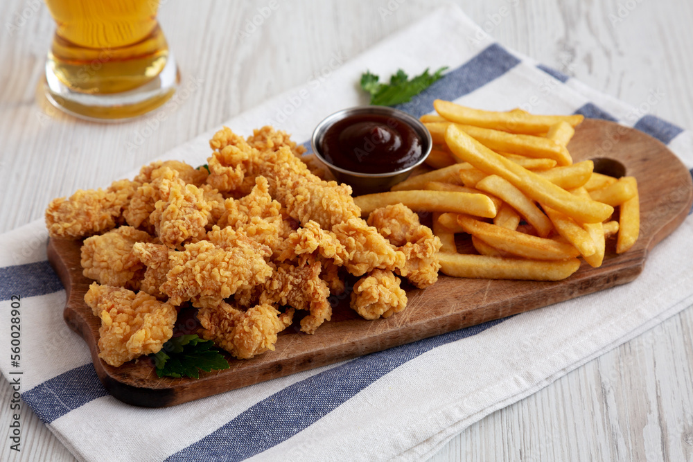 Homemade Popcorn Chicken with BBQ Sauce on a Rustic Wooden Board, low angle view. Homemade Popcorn Chicken with BBQ Sauce on a Rustic Wooden Board, low angle view.