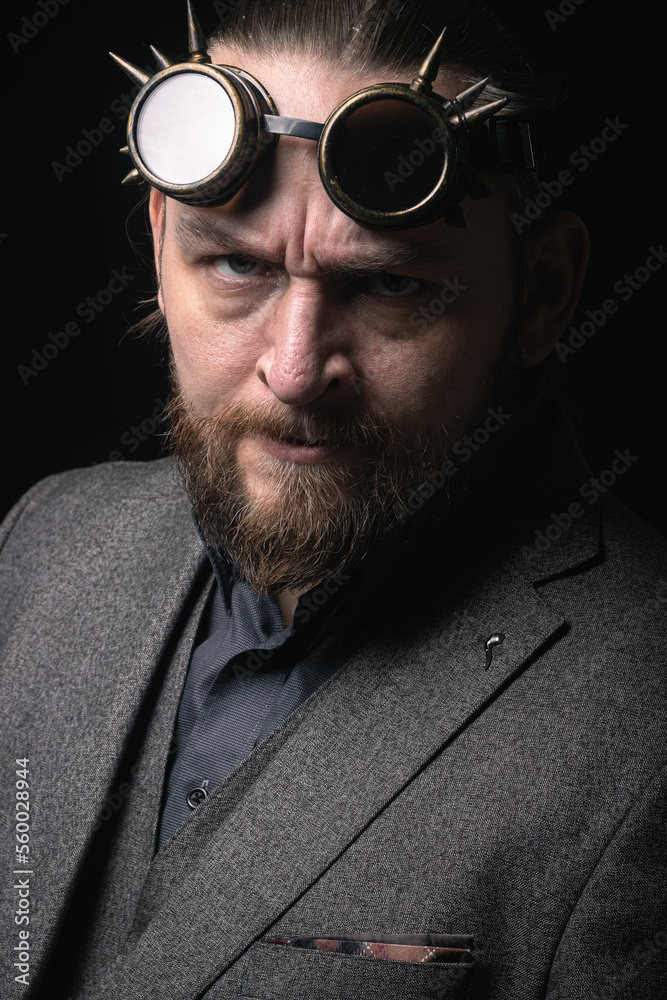 Obraz premium charismatic man in a classic suit and steampunk goggles on a black background stylish Portrait