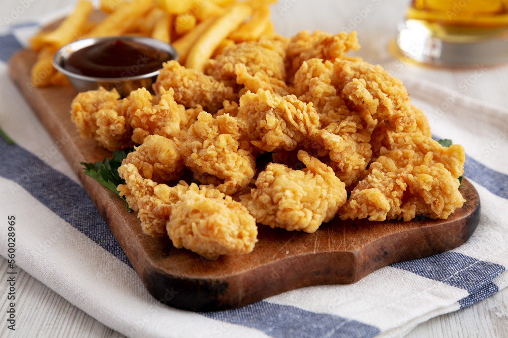 Homemade Popcorn Chicken with BBQ Sauce on a Rustic Wooden Board, side view. Close-up. Homemade Popcorn Chicken with BBQ Sauce on a Rustic Wooden Board, side view. Close-up.