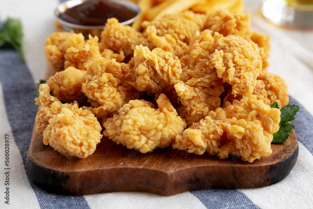 Homemade Popcorn Chicken with BBQ Sauce on a Rustic Wooden Board, low angle view. Close-up. Homemade Popcorn Chicken with BBQ Sauce on a Rustic Wooden Board, low angle view. Close-up.