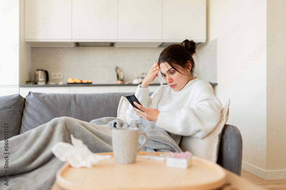 A sick young woman consults a doctor online by telephone, describes her symptoms and receives a treatment plan and medication A sick young woman consults a doctor online by telephone, describes her symptoms and receives a treatment plan and medication