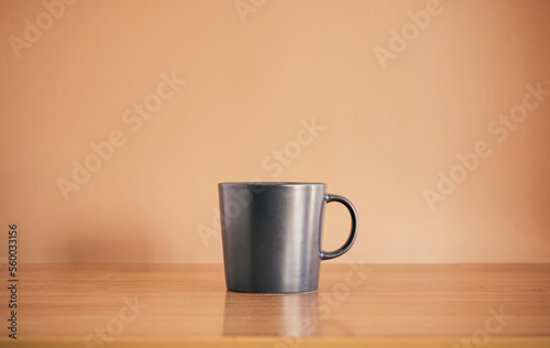 Black coffee mug on wood table with brown background