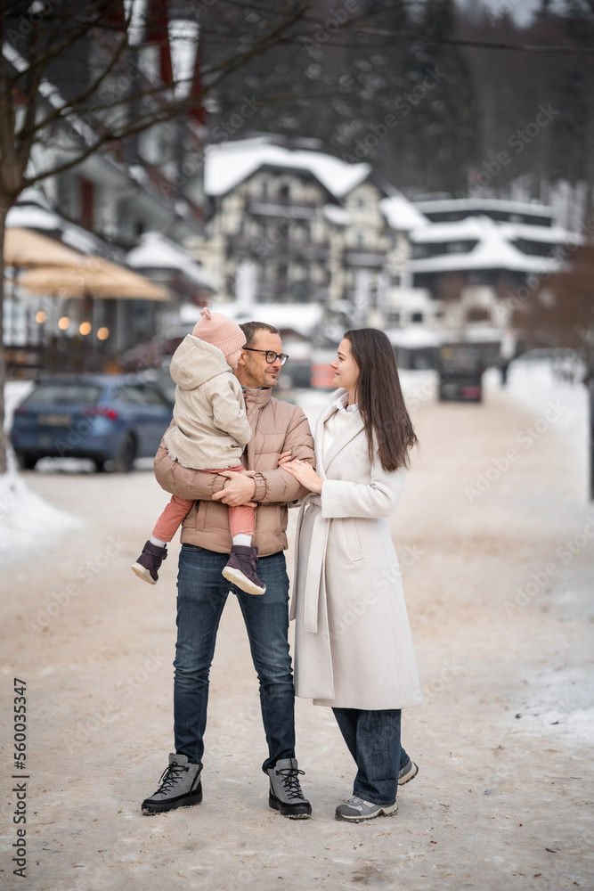 Family with little girl are having fun on snowy winter day in small town of Czech republic