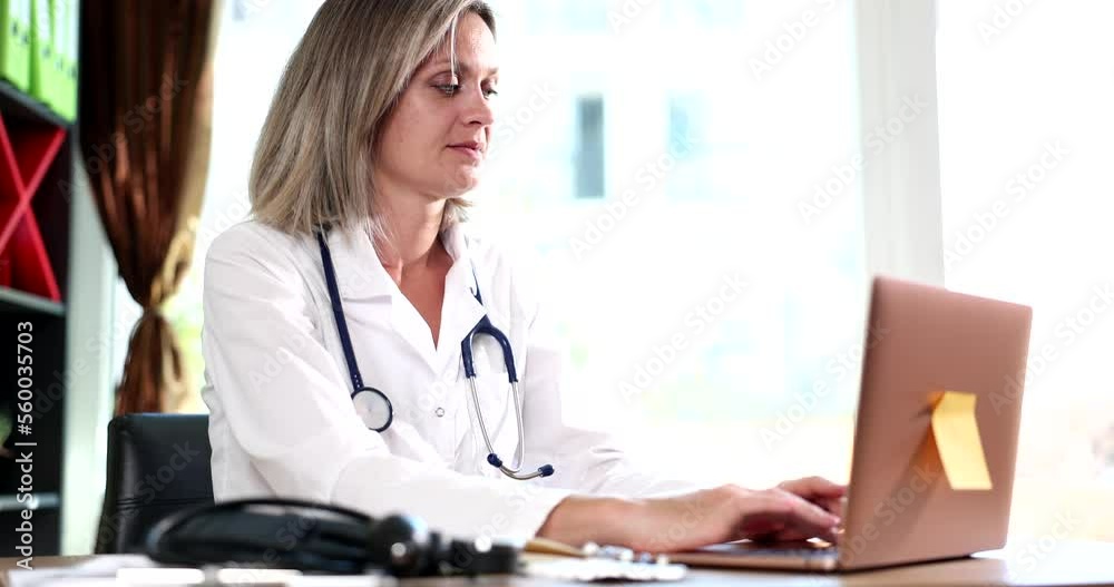 Therapist sitting at table and typing on laptop Therapist sitting at table and typing on laptop