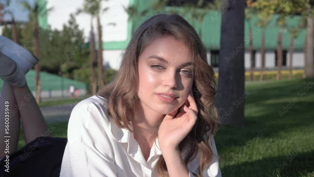 Beautiful female student or schoolgirl lies in the park on the grass. Attractive young woman in the park Beautiful female student or schoolgirl lies in the park on the grass. Attractive young woman in the park
