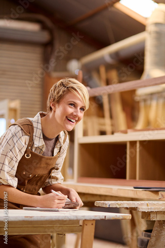 Female Apprentice Working As Carpenter In Furniture Workshop