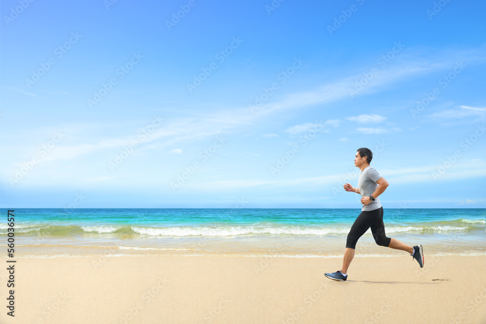 Asian man jogging on tropical sandy beach with blue sea and clear sky background. Asian man jogging on tropical sandy beach with blue sea and clear sky background.