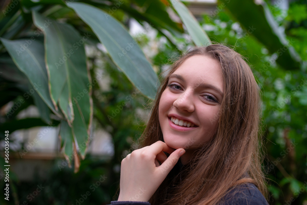 Portrait of happy beautiful young science student. Youn girl in a greenhouse with tropic plants Portrait of happy beautiful young science student. Youn girl in a greenhouse with tropic plants