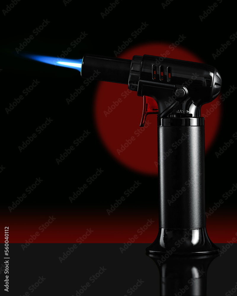 A gas blow torch kitchen with blue flame on the black background.