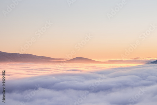 View of sea of clouds colored in the soft orange-pink hue of the morning sun. Peaks of the mountains rising out of this impermeable curtain. Sense of immortality and bliss. Beskydy, Czech republic © Fauren