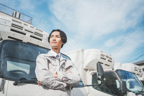 トラックの前で腕組みをする若い男性ドライバー