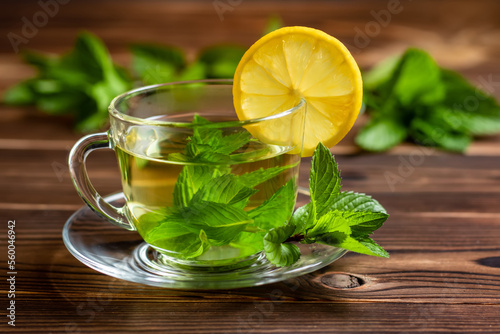 Cup of mint tea and a bunch of mint and lemon on the table